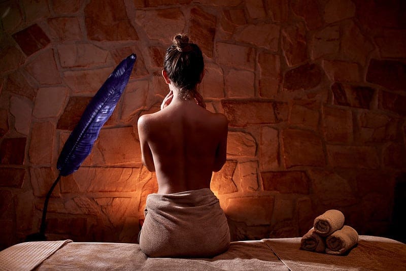 Guest on a massage table before a rustic stone wall at Zoe Spa Mykonos